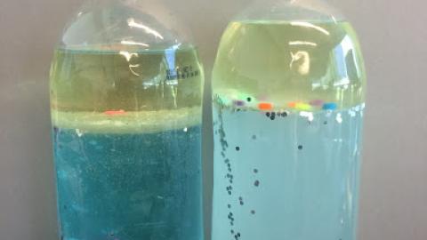 Side by side bottles with floating beads show differences between fresh and salt water