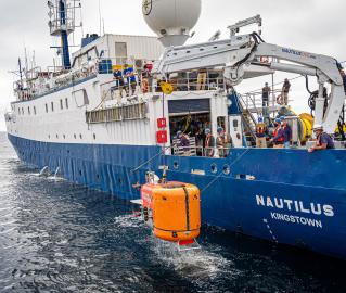 Orange underwater vehicle NUI being recovered to exploration vessel Nautilus