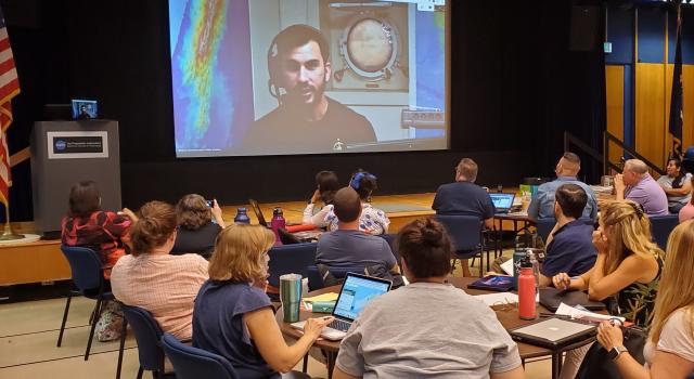 Teachers watch a screen showing Science Communication Fellow Brandon