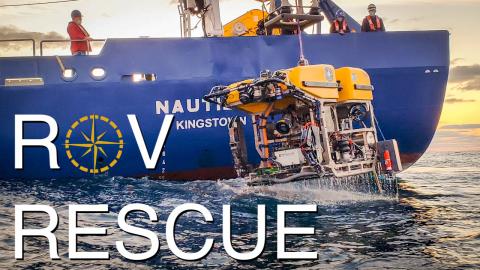 Photograph of ROV Hercules being lifted out of the water by a crane not seen at the top of the frame. The words ROV Rescue in white font are overlaid on the picture.