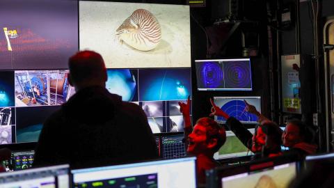 View of the control room with a nautilus on screen with smiling team members