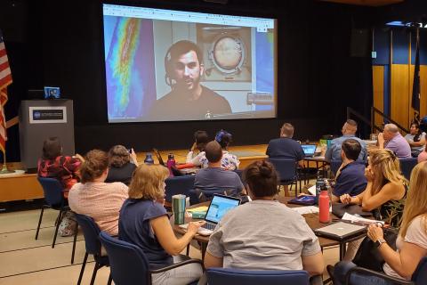 Teachers watch a screen showing Science Communication Fellow Brandon