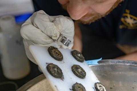 Marc Fries looks at magnet board with jeweler loop