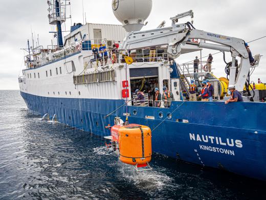 Orange underwater vehicle NUI being recovered to exploration vessel Nautilus