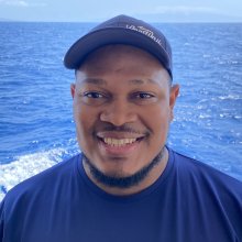 Denny headshot in front of the ocean