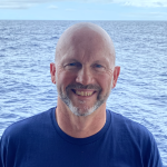 Cathal Kirwan headshot in front of the ocean 