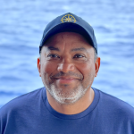 Gary Romero stands in front of the ocean 
