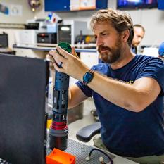Jordan Stanway repairs a Mesobot sensor between dives in the Data Lab. 