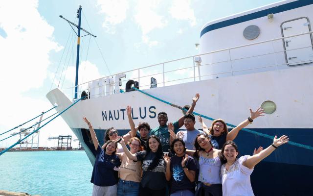 a group of students in front of a ship 