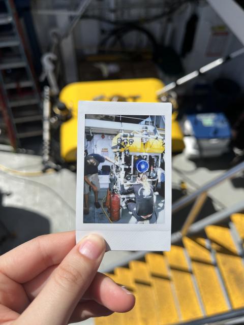 A smaller yellow ROV is worked on by Nautilus team