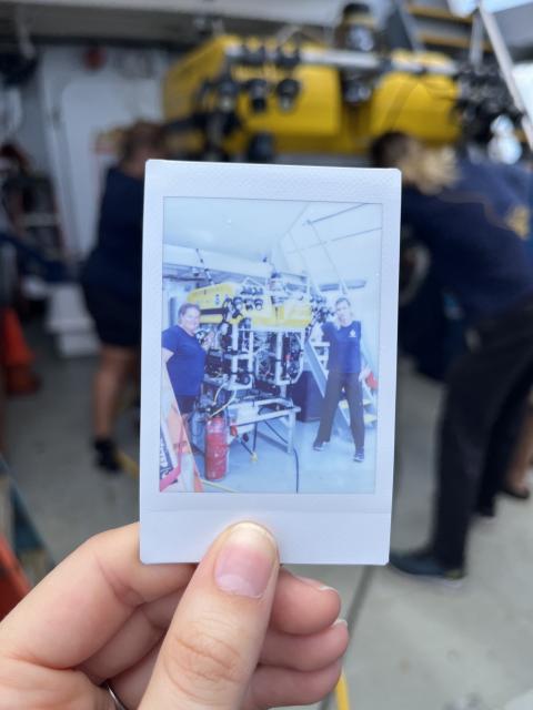 Two people pose next an ROV as they work on it