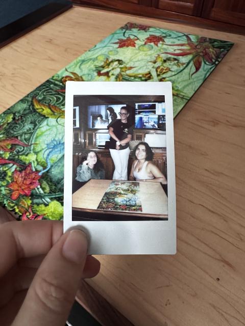 Three people pose next to an ocean themed puzzle