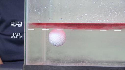 golf ball floating partway through a water column