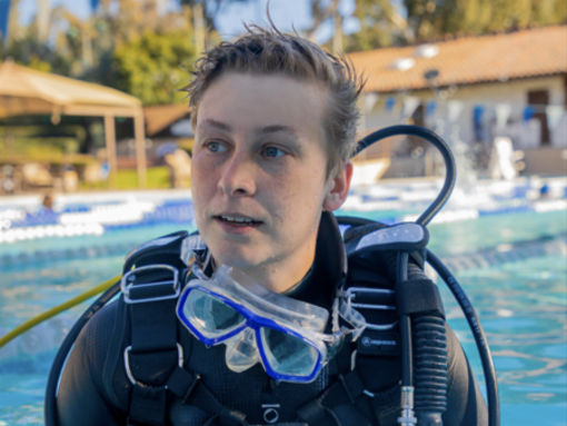 Nova emerges from a filming session, including a special camera housing to protect their camera and allow it to capture images clearly underwater.