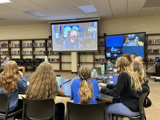 Science Communicaton Fellow Tori Hunt on a projector at the front of a classroom streaming in live to talk with students. 