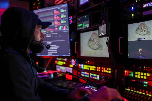 Video engineer Jacob sits in a darkened control room at the video engineering station