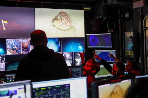 View of the control room with a nautilus on screen with smiling team members